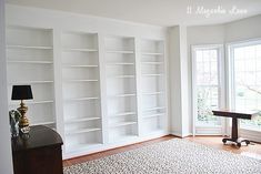 a living room with white bookcases and a black lamp on the table in front of it