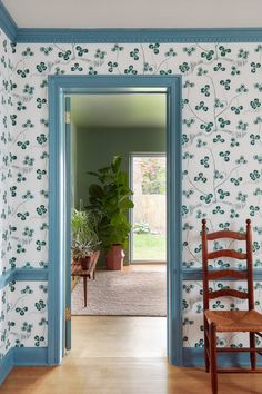 an open door leading to a room with blue trim and wallpaper on the walls