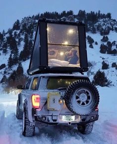 the back end of a jeep is covered in snow and has its lights turned on