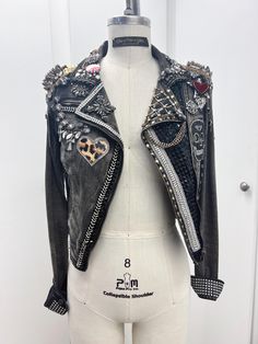 Upcycled denim moto jacket that was worn once for a photoshoot. Spiked epaulettes with chain and velveteen heart charms. Rhinestone appliques, studs, beaded trim, beads, patches, pins. This jacket is truly one of a kind! Can be worn as a statement piece, or as part of a Halloween costume (punk rocker, bad kitty...). Size S.  Some of the trims are attached by hand stitching and some is attached with glue. Studded Fitted Biker Jacket For Alternative Fashion, Fitted Studded Biker Jacket For Alternative Fashion, Trendy Fitted Biker Jacket With Rivets, Edgy Fitted Biker Jacket With Rhinestone Rivets, Fitted Edgy Biker Jacket With Rhinestone Rivets, Trendy Fitted Outerwear With Studs, Fitted Biker Denim Jacket For Winter, Edgy Fitted Outerwear With Rhinestone Rivets, Punk Style Fitted Outerwear For Festivals