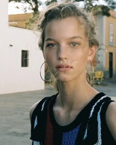 a young woman standing in front of a building with her hair blowing in the wind