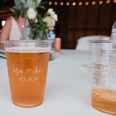 two plastic cups sitting on top of a table next to each other with writing on them