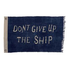 a sign that says, don't give up the ship on blue fabric with white lettering