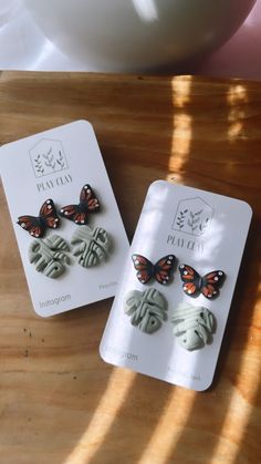 two butterfly shaped buttons sitting on top of a wooden table