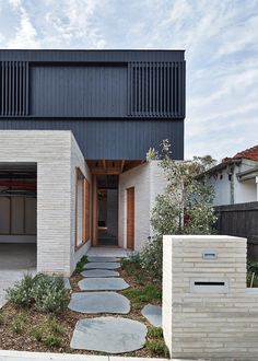 the house is made out of white bricks and has an open garage door on one side