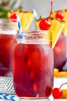 two mason jars filled with red liquid and topped with pineapple slices, cherries, and a blue and white striped straw