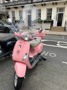 a pink scooter is parked on the side of the road in front of a building