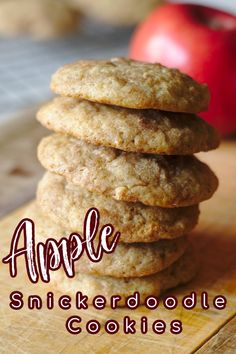 a stack of cookies sitting on top of a wooden cutting board next to an apple