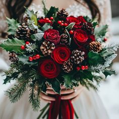 a woman holding a bouquet of red roses and pine cones