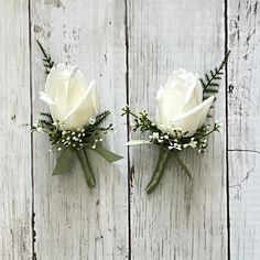 two white roses are placed on the side of a wooden wall