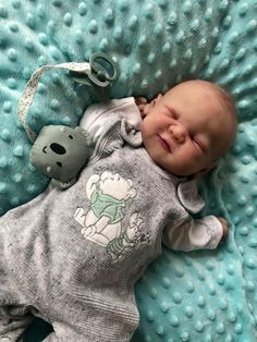 a baby is sleeping on a blue blanket with a stuffed animal in it's mouth