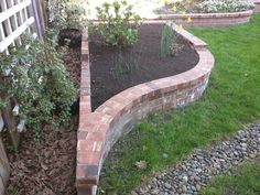 a brick garden bed in the middle of a yard