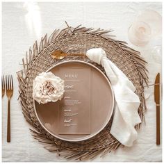 a place setting with silverware, napkins and a flower on the table cloth