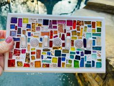 a person holding up a multicolored mosaic tile