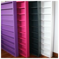 three different colored bookshelves sitting next to each other on a hard wood floor