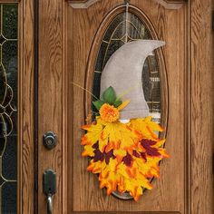 a wooden door decorated with fall leaves and a fake moon on it's side