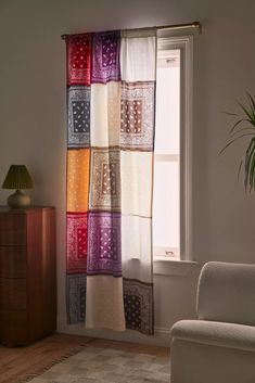 a living room with a couch, chair and window covered in multicolored curtains