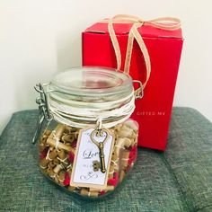 a glass jar filled with lots of corks next to a red gift box on top of a couch