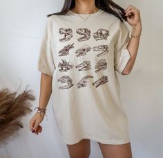 This Dinosaur Skeleton Tshirt is a perfect dinosaur gift for dinosaur lovers likes tyrannosaurus rex T-Rex, Parasaurolophus, velociraptor and more. Perfect to wear at fossil hunting, museums trips or a dinosaur theme birthday parties. For other dinosaur items, click here: https://www.etsy.com/shop/TheNims?search_query=dinosaur Browse through my other awesome items here: http://thenims.etsy.com/ UNISEX TEES Gildan 5000™ (CUSTOMER FAVORITE) * 100% Cotton (fiber content may vary for different color Summer Dinosaur Print Relaxed Fit Tops, Dinosaur Print Relaxed Fit Tops For Summer, Summer Cotton Shirt With Dinosaur Print, Relaxed Fit Dinosaur Print Top For Summer, Dinosaur Print Graphic Tee For Summer, Graphic Tee With Dinosaur Print For Summer, Summer Dinosaur Print Graphic Tee, Cotton Short Sleeve Shirt With Dinosaur Print, Summer Dinosaur Print Shirt With Crew Neck