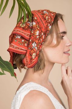 a woman wearing a red bandana with flowers on it's head and palm tree in the background