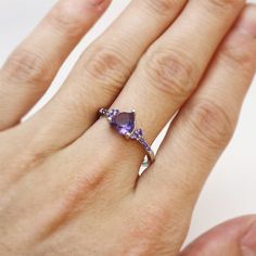 a woman's hand wearing a ring with an amethorate and diamond