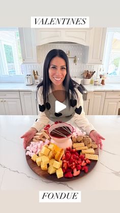 a woman sitting in front of a platter filled with different types of food on top of a kitchen counter