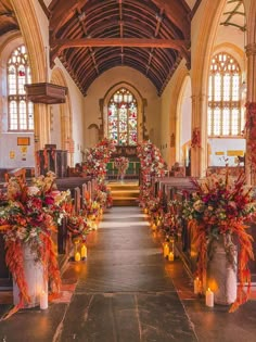 an aisle lined with candles and flowers in front of a church