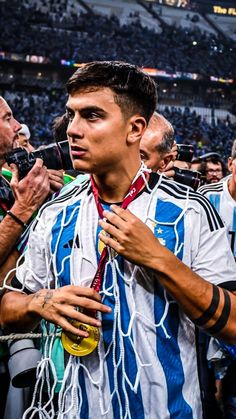 a soccer player is standing in front of the crowd with his medal around his neck