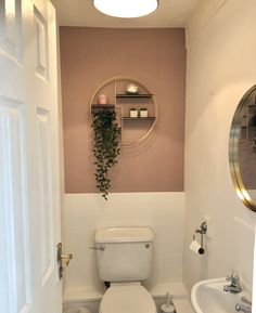 a white toilet sitting next to a sink in a bathroom under a round light fixture