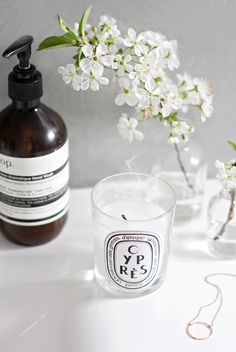 a bottle of soap next to a glass filled with liquid on a white counter top