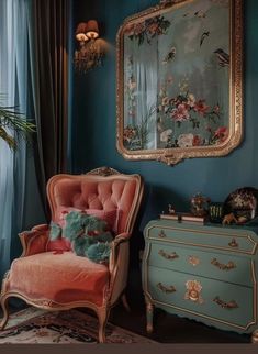 a chair and dresser in a room with blue walls, gold trimmings and paintings on the wall