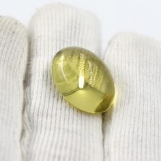 a gold colored pill sitting on top of a white pair of gloves and sweaters