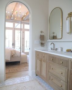 a large bathroom with double sinks, mirrors and a door leading to the bedroom area