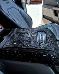 the inside of a car with black leather seats and an intricate design on it's seat