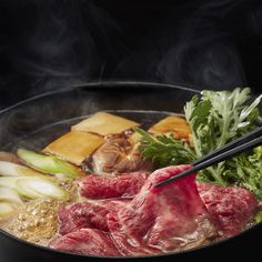 meat and vegetables cooking in a wok with chopsticks sticking out of it