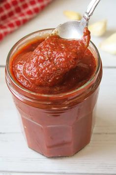 a spoon full of sauce sitting in a jar