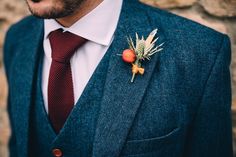 a man wearing a suit and tie with a boutonniere on his lapel