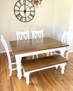 a wooden table with white chairs and a clock on the wall