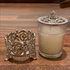 a candle next to a glass container on a wooden table