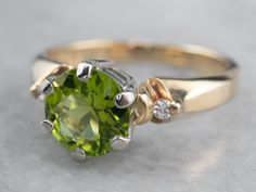 This classically designed ring is timeless and goes with everything! Floating diamonds adorn the shoulders and serve to accent the peridot at the center. The peridot itself is a lovely yellow-green color that is complimented beautifully by the richness of the gold band. Metal: 14K Yellow and White Gold Gem: Peridot 1.66 Carats Gem Measurements: 7.7 mm, Round Accents: 2 Diamonds totaling .04 Carats, H in Color, S1 in Clarity Ring Size: 7.50 Marks: "TG(C)14K USA" Stamped on the inside band Luxury Peridot Birthstone Ring With Accent Stones, Luxury Peridot Birthstone Ring, Gold Peridot Ring, Diamond Ring Yellow Gold, Yellow Gold Sapphire Ring, Band Metal, Peridot Jewelry, Cameo Ring, August Birthstone