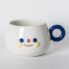 a close up of a cup with a smiley face on the front and blue handles