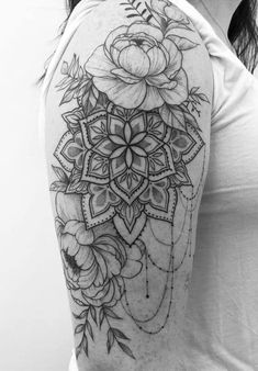 a woman's shoulder tattoo with flowers and leaves on the back of her arm