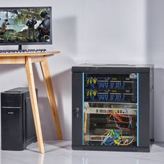 a desktop computer sitting on top of a wooden desk next to a small cabinet filled with wires