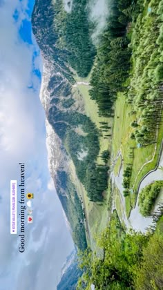 an aerial view of a mountain with trees on the side and clouds in the sky