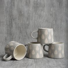 four coffee mugs stacked on top of each other in front of a concrete wall