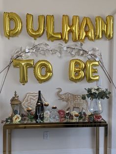 a table with balloons and decorations on it in the shape of letters that read dulhan to be