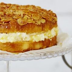 a cake with almonds on top sitting on a glass plate