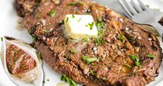 steak with butter and parsley on a white plate next to an open oyster shell