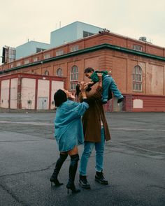 two people standing in the middle of an empty parking lot, one is holding a child on his shoulders