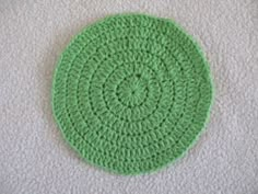 a green crocheted doily sitting on top of a white blanket